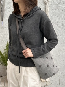 Dettaglio della borsa a secchiello in feltro grigio con pois 3D e maglione in maglia