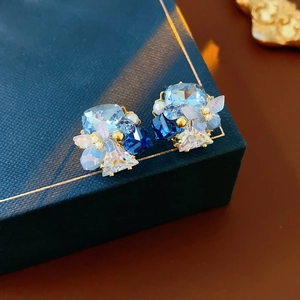 Detail shot of gold-plated butterfly earrings with blue crystals and mini pearls