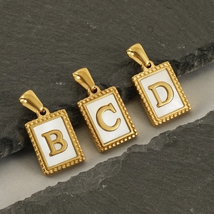 Detail von rechteckigen Goldanhängern mit Buchstaben B, C, D und weißer Einlage