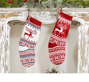 Detail of red and white knitted Christmas stockings with reindeer patterns on mantel
