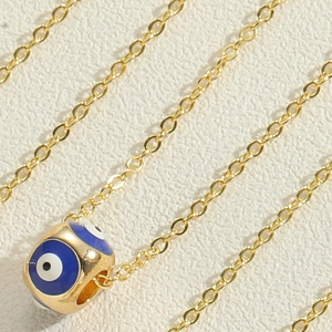 Detailed close-up of golden chain and blue enamel evil eye pendant charm necklace
