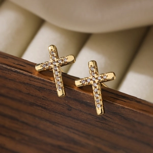 Classic 18K gold plated cross stud earrings with white zircon crystals on a wooden stand