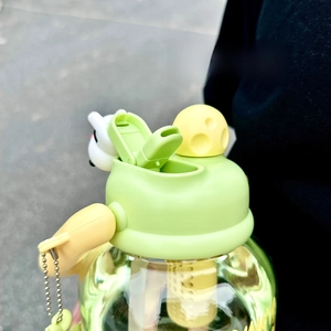 Detail of the bottle's push-button lid and drinking nozzle with a cute cow charm