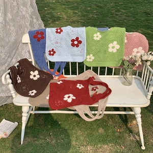 Details der Stricktextur und Blumenapplikationen auf bunten Häkel-Einkaufstaschen im Freien
