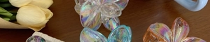 Detailed view of iridescent plumeria hair claws on a dark wood table with tulips