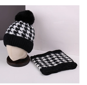 Detail view of thick houndstooth knit beanie with large fur pom and matching neck warmer