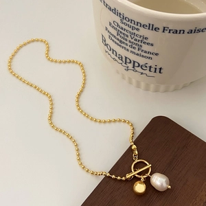 Détail d'un collier de perles d'eau douce avec fermoir OT sur une tasse française blanche