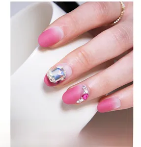 Macro detail of matte gradient pink press-on nails with large rhinestones and heart gems