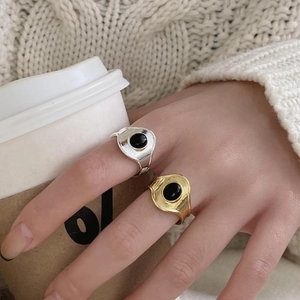 Minimalist silver and gold rings with black agate worn against a knit sweater background