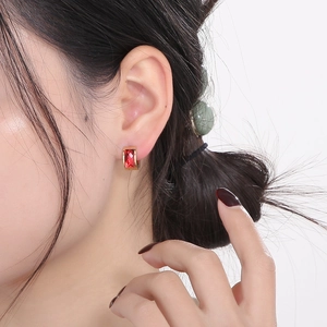 Close-up of model wearing rectangular red gemstone earrings with golden settings