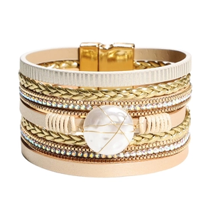 Dettaglio macro di bracciale multistrato in pelle beige con strass e perla centrale