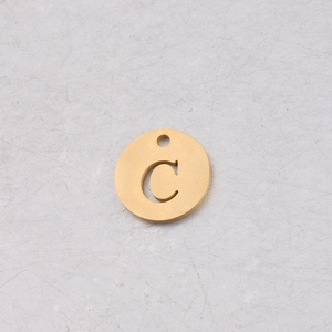 Détail macro du pendentif rond 12mm en acier doré avec lettre C évidée