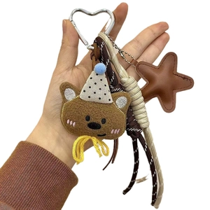 Brown plush bear keychain with polka dot hat and silver heart clasp on white background