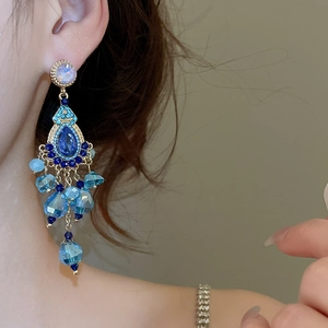 Macro detail of vintage tassel earrings with blue crystals and gold-plated finish