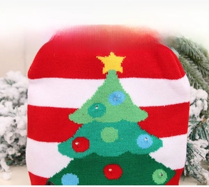 Detail of knitted Christmas tree pattern with sequins on red and white striped fabric