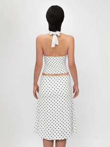 Detailed back view of a white polka dot halter crop top with a large bow tie knot