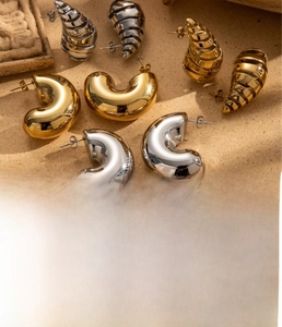 Detailed macro view of gold and silver chunky croissant twisted titanium steel earrings
