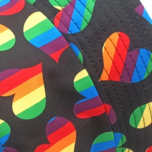 Detail of embroidered rainbow heart pattern on black fabric of a reversible bucket hat