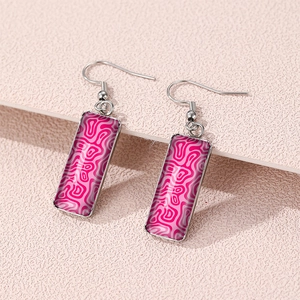 Detailed close-up of pink and magenta wavy pattern earrings with silver hooks