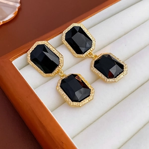 Detail of vintage geometric earrings with black gems in a white velvet box