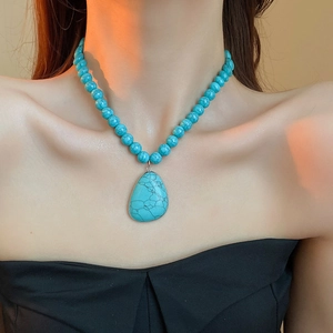 Close-up of bohemian turquoise beaded necklace with large stone pendant on a model