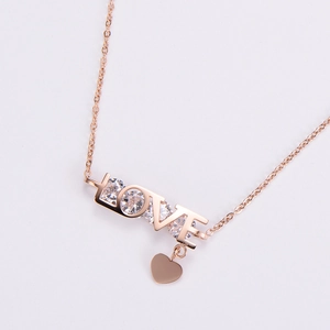 Macro detail of rose gold LOVE letter pendant with sparkling crystals and heart charm