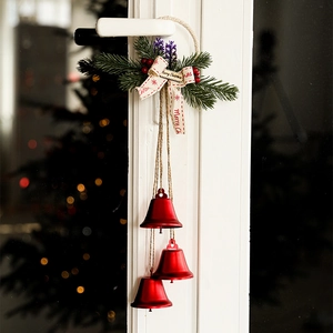 Christmas door hanger with red metal bells, green pine needles and Merry Christmas ribbon