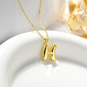 Dettaglio ravvicinato del ciondolo a lettera H in stile palloncino dorato 18K su collana