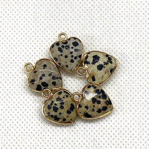 Macro shot of five heart-shaped Dalmatian Jasper pendants with gold plated edges for DIY