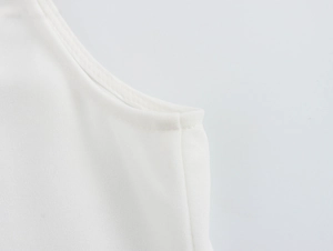 Detailed macro view of high-quality double-stitched hem on a white beaded camisole top