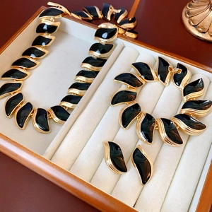 Détail de parure bijoux feuille vintage avec émail noir et cadre doré dans un coffret bois