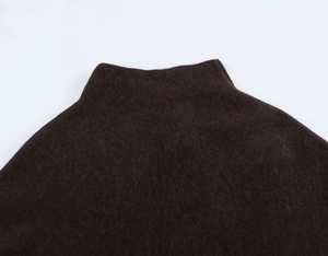 Close-up of the mock neck collar and soft knitted texture of the dark brown poncho jacket