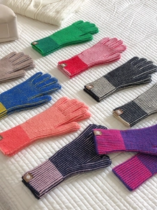 Plano detalle de guantes de punto coloridos en varios tonos sobre una tela blanca acolchada