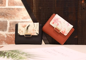 Détail de portefeuilles courts en cuir noir et orange avec imprimé fleuri et fermoir doré