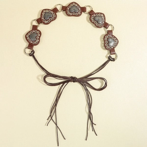 Detail of brown western belt with silver heart studs and eyelets on textured paper