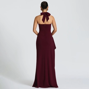 Detail of burgundy backless halter dress featuring a large bow and elegant high slit