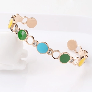 Macro view of rose gold C-shaped cuff with colorful enamel circles and sparkling crystals