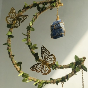 Detail of crescent moon pendant with hemp rope, green leaves and blue raw crystal