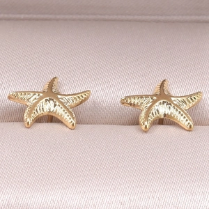 Macro detail of gold starfish stud earrings in 304 stainless steel with textured surface