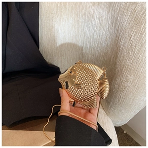 Detail of a gold fish-shaped mini clutch bag with textured scales and fine metal chain