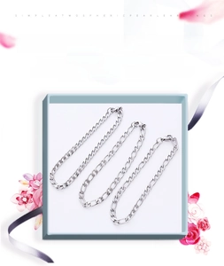 Close-up of Figaro and Cuban link stainless steel chains presented in a jewelry box