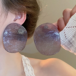 Close-up of large purple acrylic earring with matte texture on female model's ear