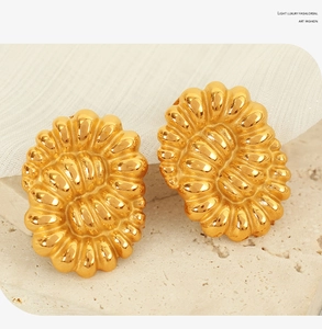 Detail view of gold vintage earrings with textured oval sunburst relief pattern