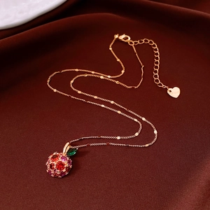 Close-up of 14k gold plated apple pendant necklace with red and pink zircon gems
