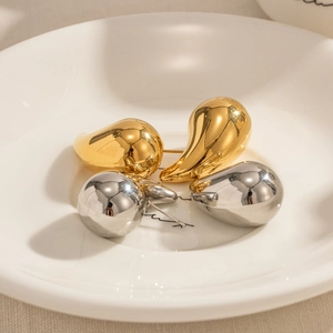 Detailed macro view of gold and silver teardrop earrings on a white ceramic plate