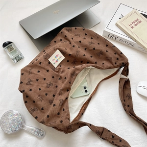 Nahaufnahme braune Cord-Umhängetasche mit schwarzen Herzprints und Logo-Details