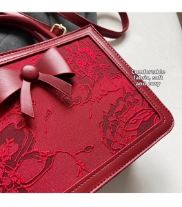 Close-up of red lace embroidery and 3D leather bow detail on a luxury bridal handbag