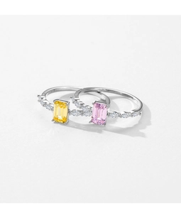 Close-up of pink and yellow rectangular gemstone rings with diamond-encrusted silver bands