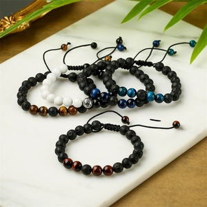 Bracelets en œil de tigre et pierre de lave sur marbre blanc avec feuilles vertes