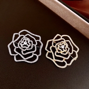 Détail macro d'une broche camélia avec pavé de zircons étincelants en argent et or